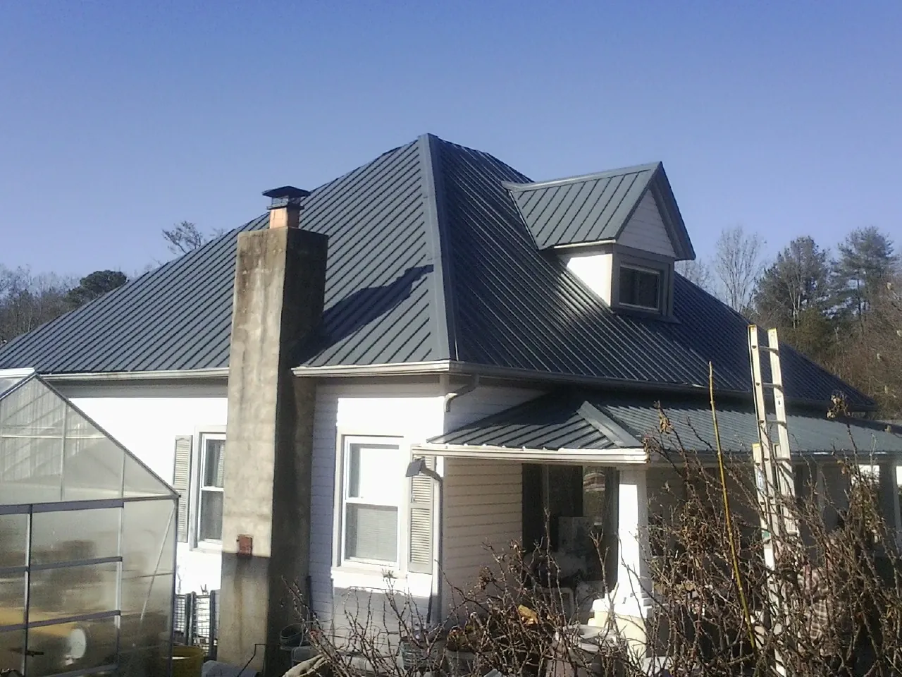 Dark blue standing seam metal roof on a white farmhouse with dormer — Slate & Tile Roof Repair by Roofing Brothers in Rineyville