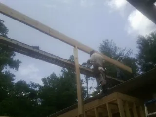 Carpenter setting a ridge beam over a new addition frame — Ice Dam Removal by Roofing Brothers in Rineyville