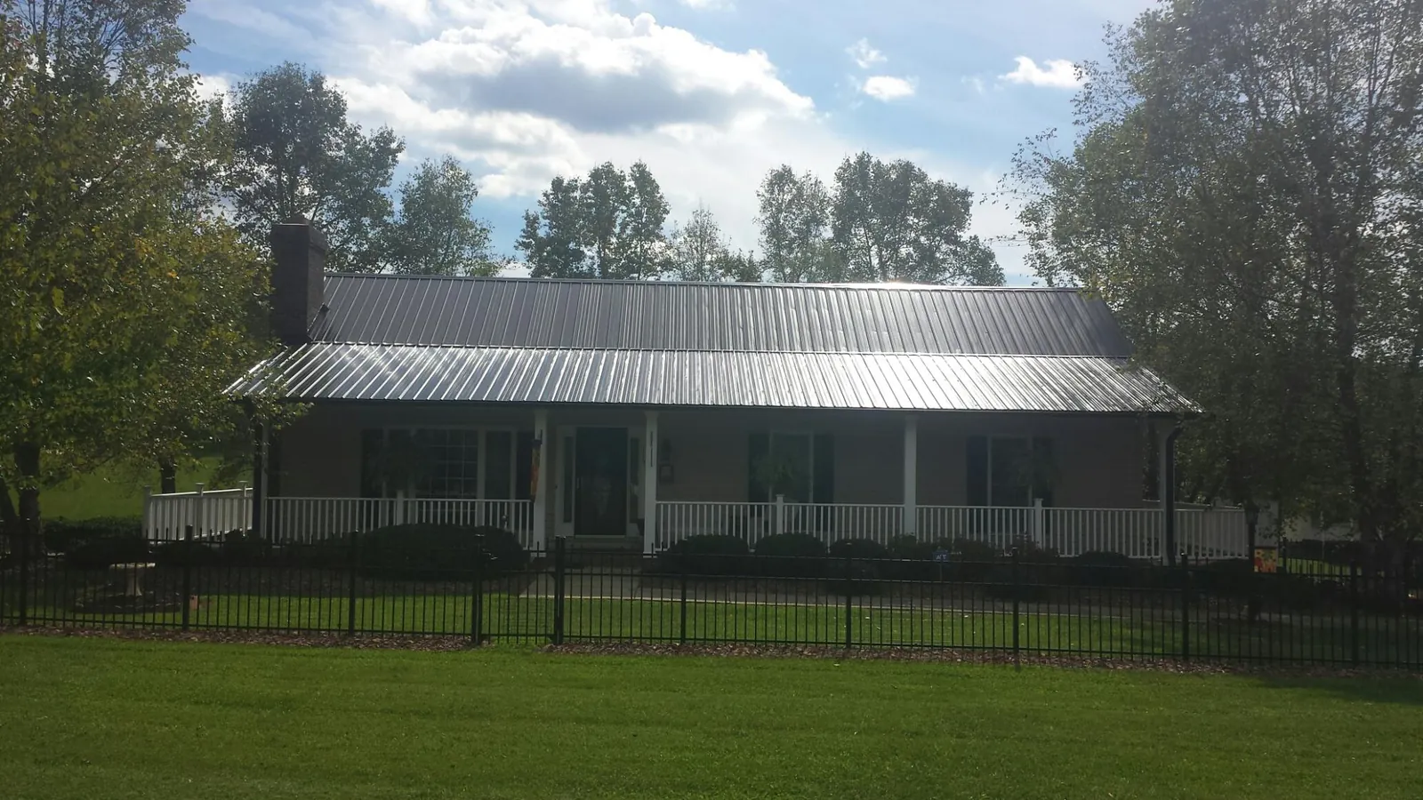 Gray metal roof on a brick ranch with a full width front porch — Gutter Guard Installation work by our crew in Rineyville