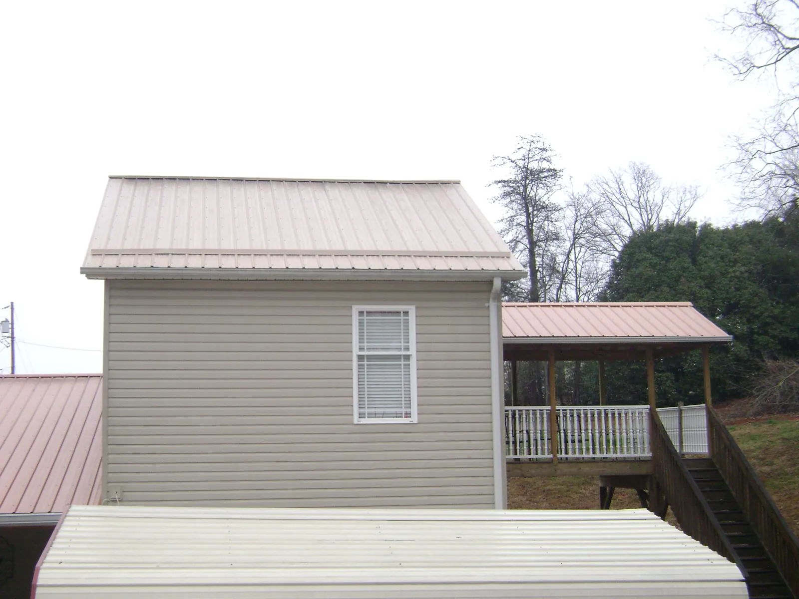 Tan metal roofs on a two story addition and attached porch, from a Roof Replacement job in Rineyville