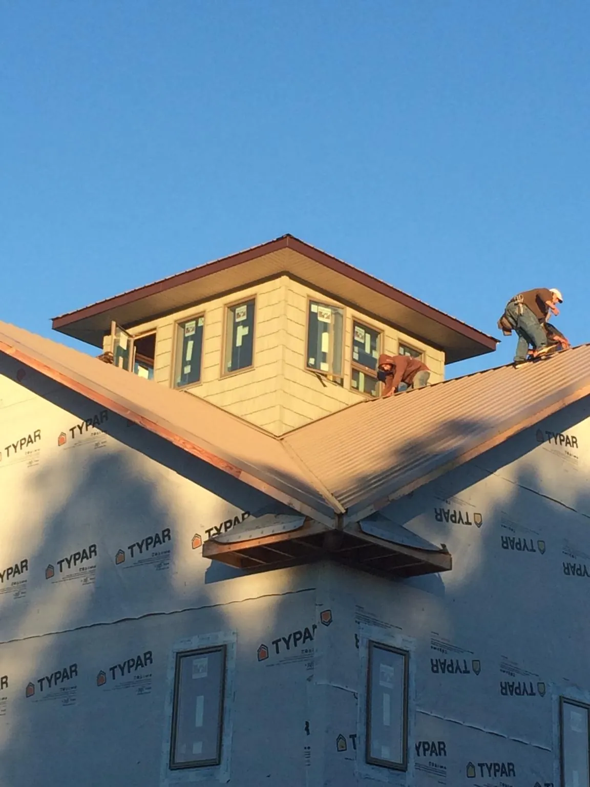 Roofers working around a rooftop cupola on a new metal roof at sunset — Roof Waterproofing in Rineyville by Roofing Brothers